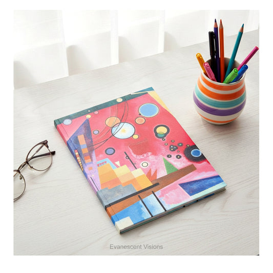 A hardcover notebook with a cover featuring a colorful abstract geometric design titled 'Schweres Rot' by Kandinsky, shown on a desk with desk clutter.