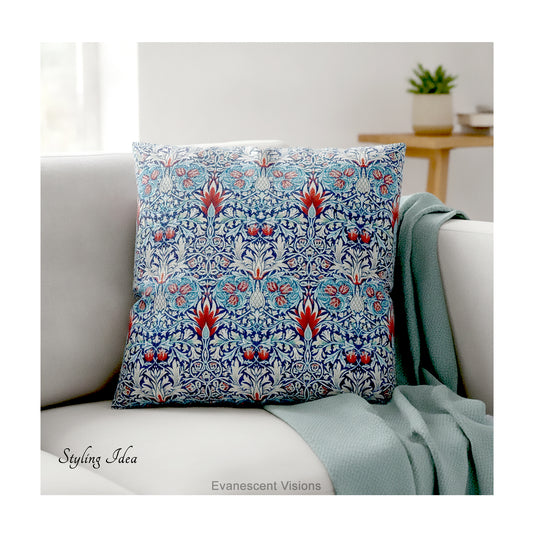 A square decorative cushion with red and blue floral themed pattern entitled 'Snakeshead' by William Morris, on cream coloured sofa