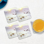 4 coasters with a print of the snowy winter landscape painting 'Southland Hills' by Farquharson, shown on a marble kitchen table with a glass and teacup. 