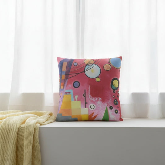 A colourful square cushion featuring an abstract art print of Schweres Rot (Heavy Red) by abstract artist Wassily Kandinsky, styled on a white window seat. 