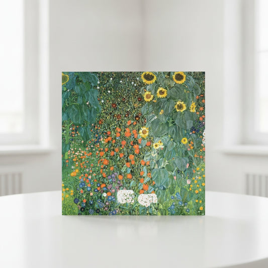A square art print greeting card featuring Gustav Klimt's sunflower and wildflower painting, displayed on a white table.