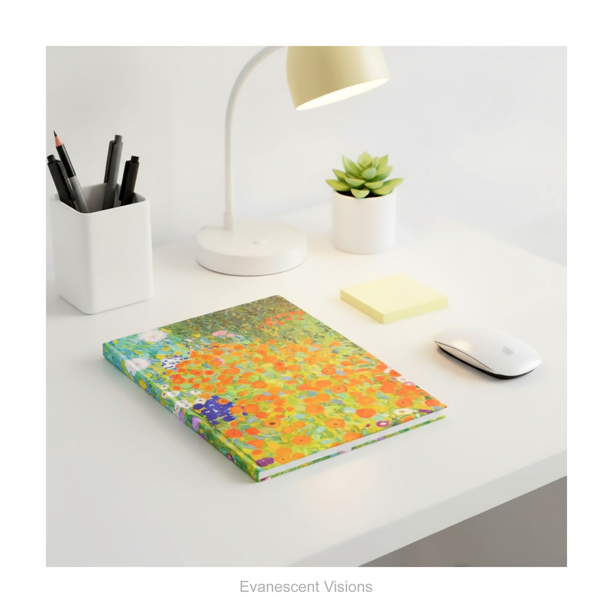 A hardback notebook featuring the colourful impressionistic floral artwork 'Bauerngarten' by Gustav Klimt, shown lying on a white desk with desk accessories.