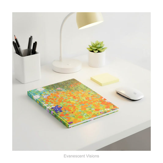 A hardback notebook featuring the colourful impressionistic floral artwork 'Bauerngarten' by Gustav Klimt, shown lying on a white desk with desk accessories.