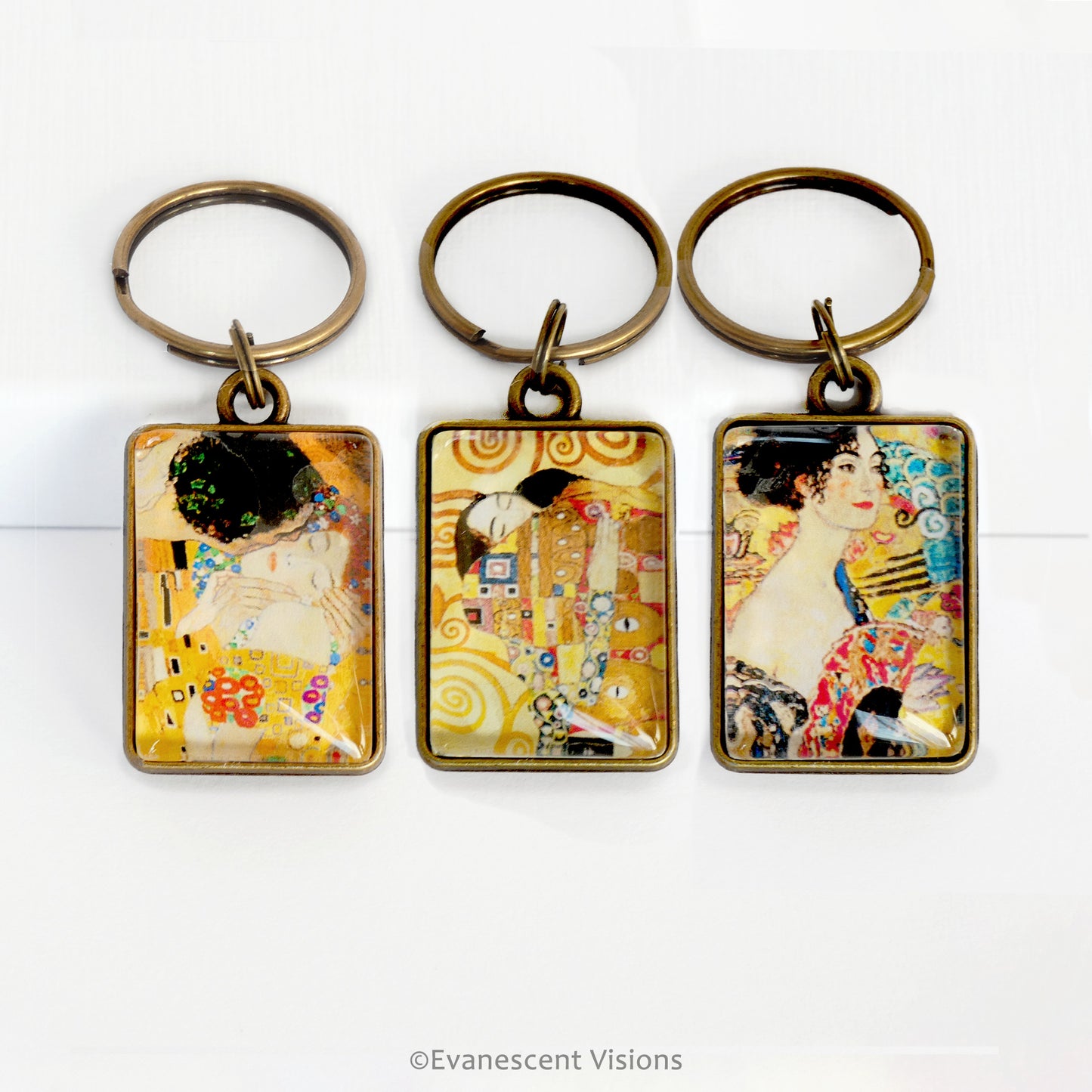 Three keychains with artistic designs by Gustav Klimt on a white background