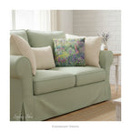 A square decorative cushion featuring an impressionist floral artwork 'The Artist's Garden' by Claude Monet, on a pale green sofa. 