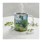 'View of Vétheuil' Mug styled on a table with green leaves.