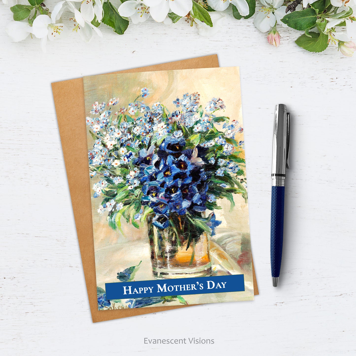 Card and envelope on white surface. Card has painting, 'Spring Flowers in a Glass Vase' by Rosa Scherer  and 'Happy Mother's Day' on front. By the side of the card rests a pen and above white blossom.
