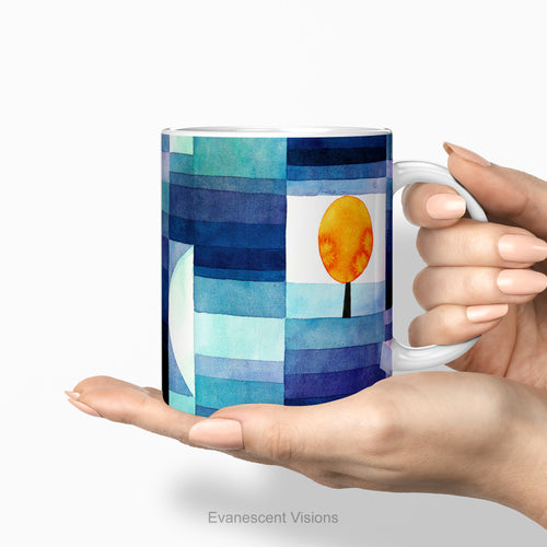 Hands holding a ceramic mug featuring a watercolor-style abstract landscape print called 'Harbinger of Autumn' by Paul Klee