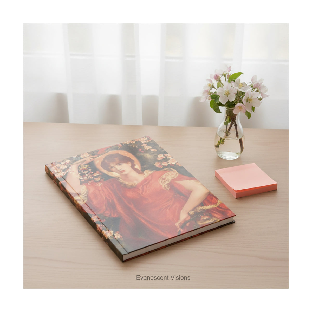 A hardcover notebook with a print of painting 'Fiammetta' by Rossetti, laying on a wood desk. 