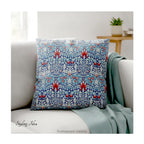 A square decorative cushion with red and blue floral  themed pattern entitled 'Snakeshead' by William Morris, on cream coloured sofa