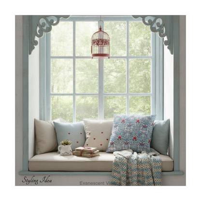 A square decorative cushion with red and blue floral  themed pattern entitled 'Snakeshead' by William Morris, on a window seat.