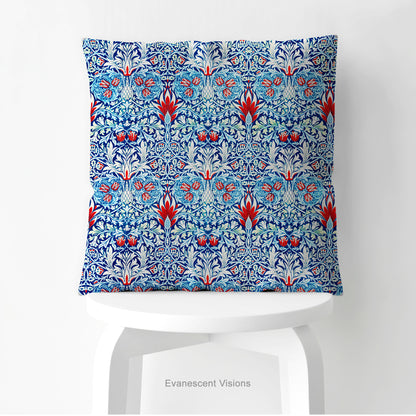 A square  cushion with a print of William Morris pattern Snakeshead, shown standing on a white stool. 