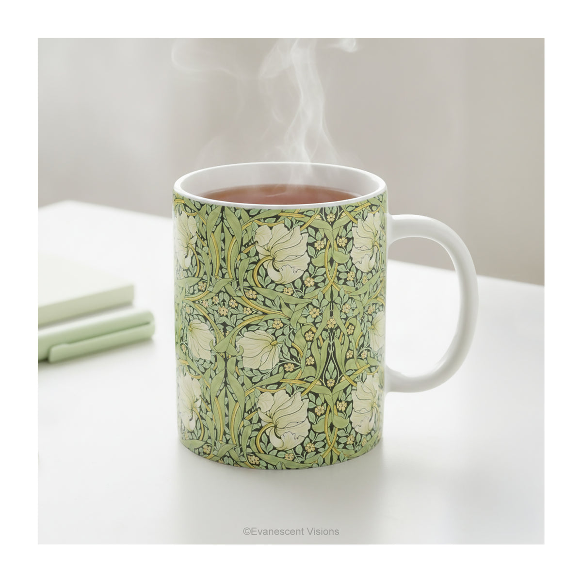 A ceramic mug styled on a table with floral patterned artwork titled 'Pimpernel' by William Morris. 