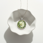 Double sided pendant necklace with design 'Pimpernel' by William Morris displayed on a white ceramic dish.
