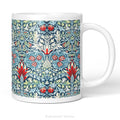 A white ceramic mug featuring a detailed, symmetrical floral pattern in navy blue, sage green, and red called Snakeshead by William Morris,   shown on a clean white background .