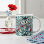 A ceramic mug with detailed blue, red, and cream symmetrical floral pattern called Snakeshead  by William Morris set on a white table.