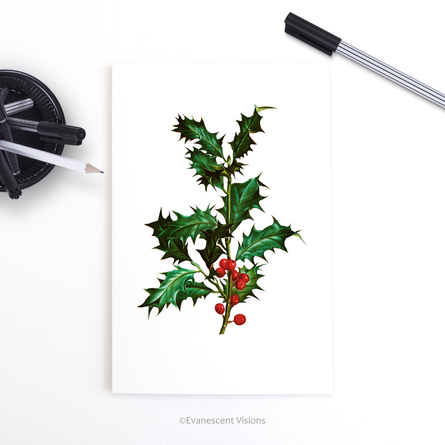Holly Christmas Greeting Card on a desk with pens
