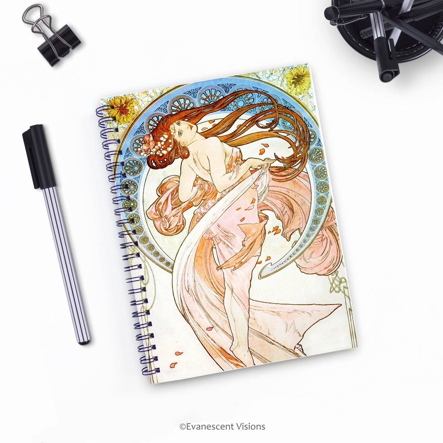 top down view of Mucha Dance Art Nouveau Style Spiral Bound Notebook with pens on a desk